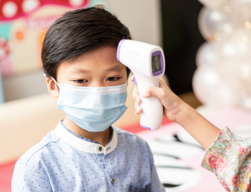 kid wearing mask getting temperature check