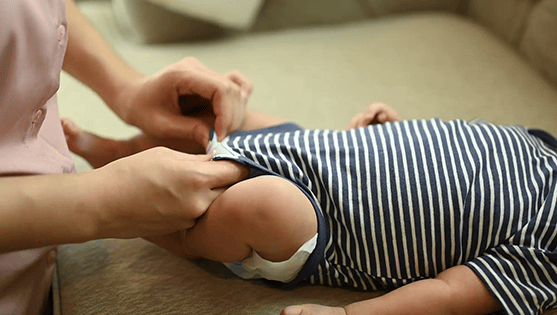 Close-up of a caregiver changing a baby's diaper, gently adjusting the clothing on the baby